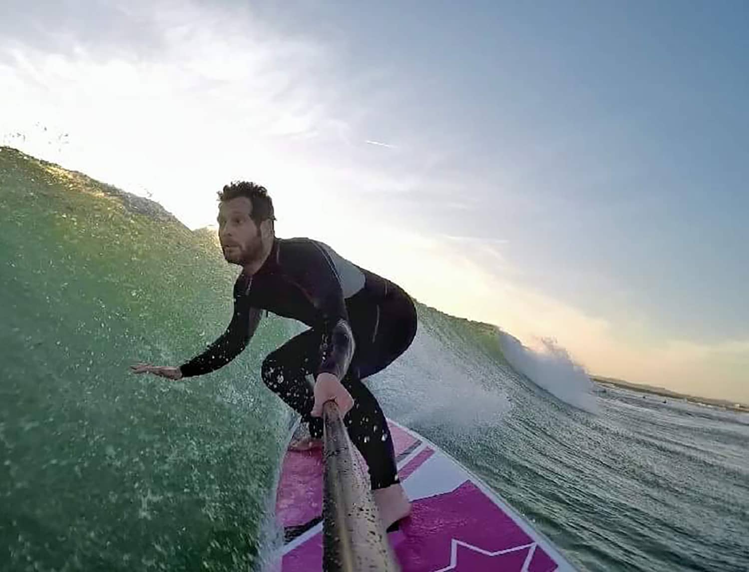 Surfista bajando una ola de derechas con una tabla Evo Rosa