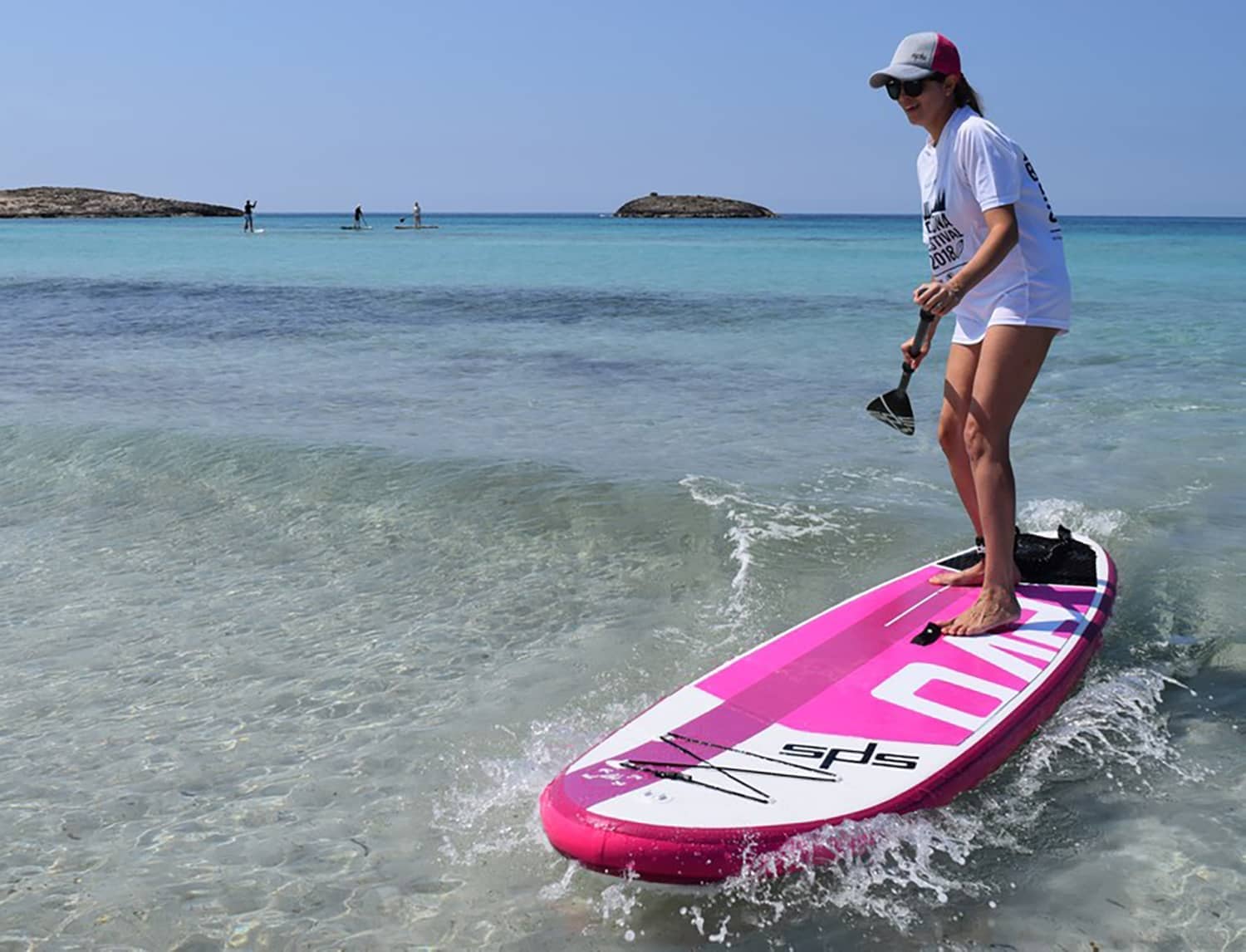 Chica con gorra surfeando una ola pequeña con una tabla Evo Rosa